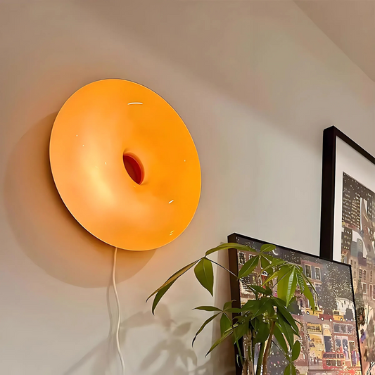 Bauhaus-style donut LED table lamp in bold orange with USB plug-in base on white nightstand