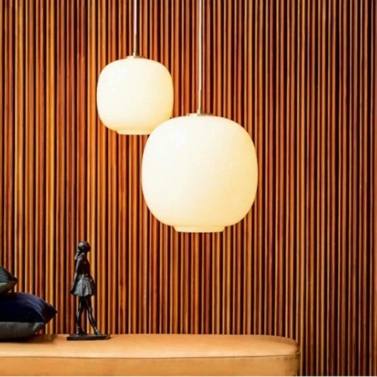 Glass pendant lights featuring a minimalist milky sphere and iron finish.