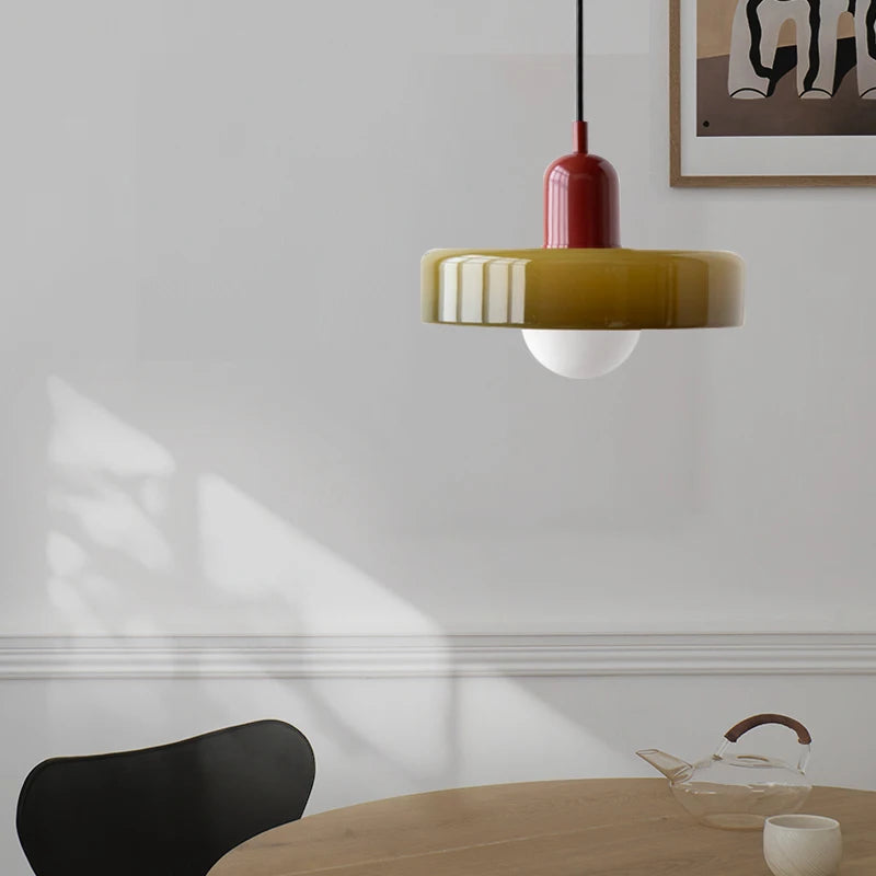 Modern pendant light hanging above a dining table with a black chair and decorative items.