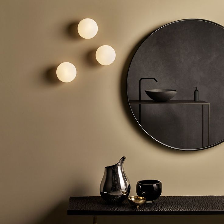 Contemporary bathroom vanity with marble top and round white wall light.