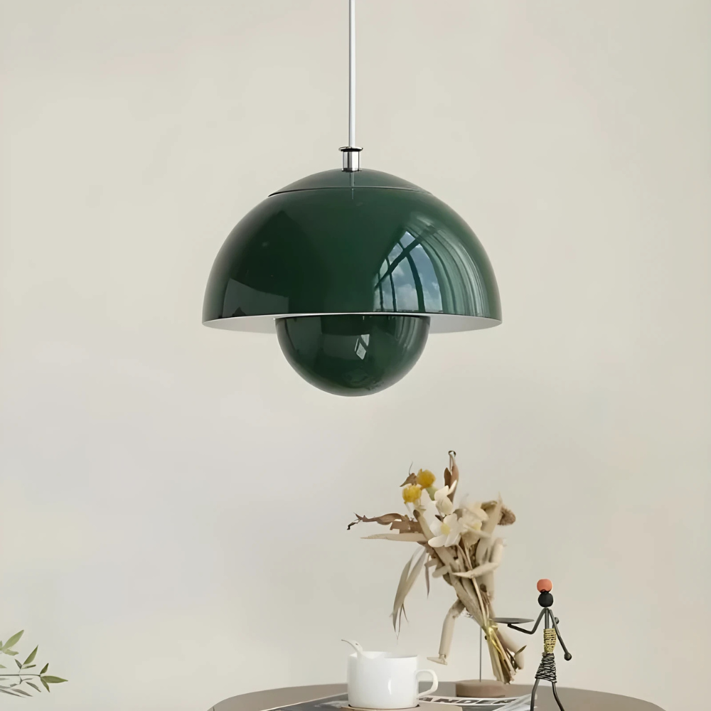Green pendant lamp hanging above a table with decorative items on a light background