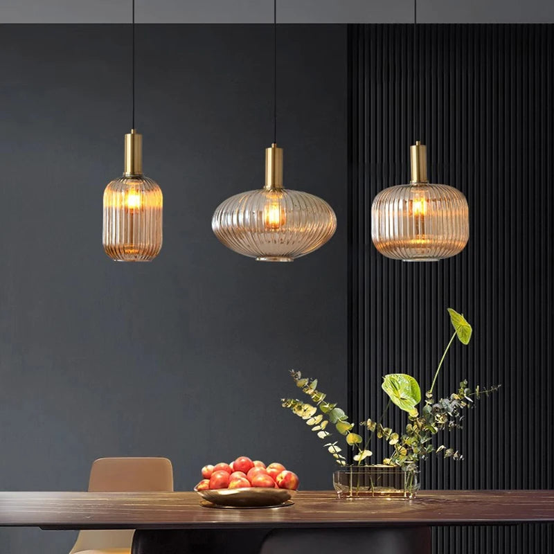 Three pendant lights hanging above a dining table with a dark wall background