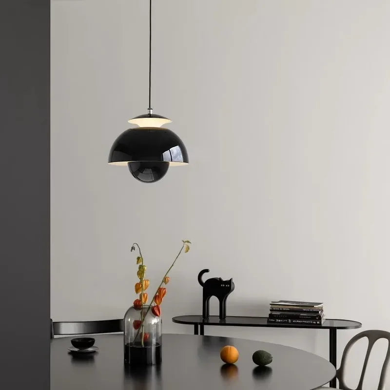 Modern nordic black pendant lamp hanging above a dining table with decorative items.