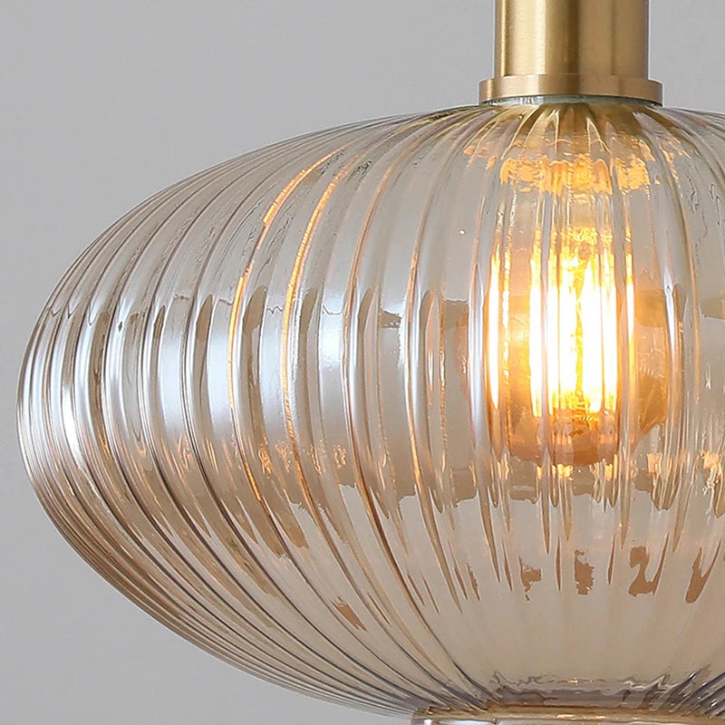 Close-up of a glass pendant light with a gold fixture on a gray background