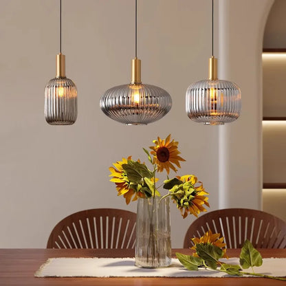 Three pendant lights hanging above a dining table with sunflowers in a vase.