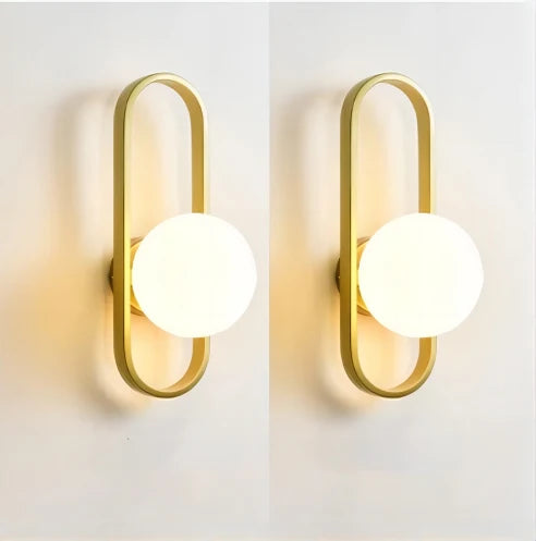 Two gold wall sconces with white glass shades on a light gray background