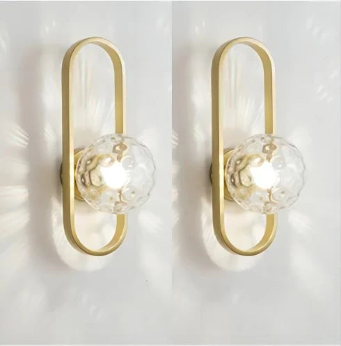 Pair of gold wall sconces with glass globe lights on a white background
