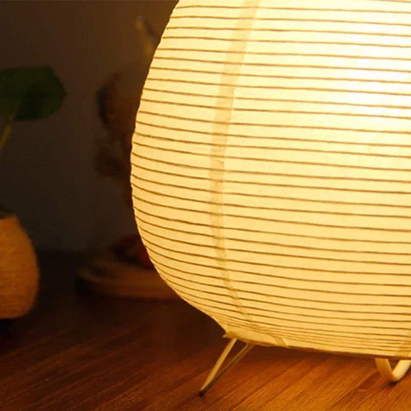 Japanese lantern ambiance provided by a sculptural rice paper lamp on a wooden nightstand.