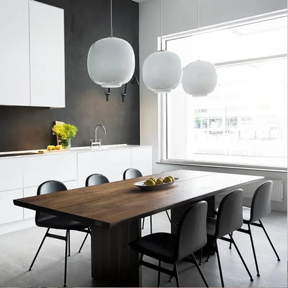 White glass ball hanging lamp over a contemporary restaurant dining table.