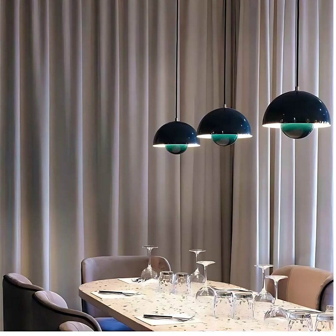 Puspa Forest Green Bauhaus-style flowerpot pendant lights in dark green hanging above a modern dining table with terrazzo surface and soft beige curtains. Minimalist Nordic interior design lighting.